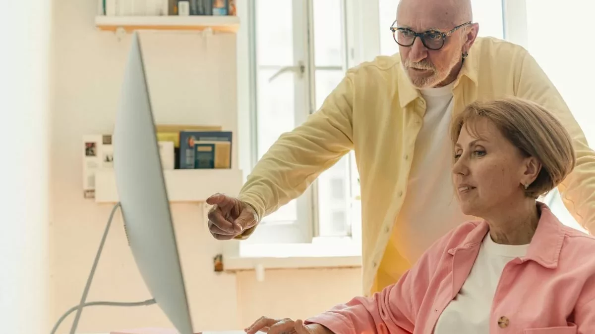 Personne senior devant un ordinateur tout-en-un pendant une initiation informatique à domicile