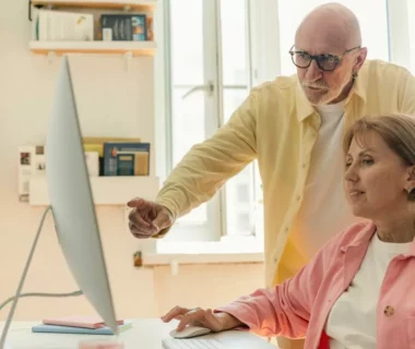 Personne senior devant un ordinateur tout-en-un pendant une initiation informatique à domicile
